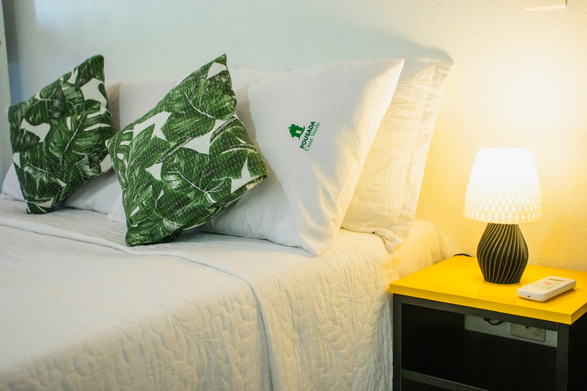Cama da Pousada Casa Verde com travesseiro bordado e detalhes em verde